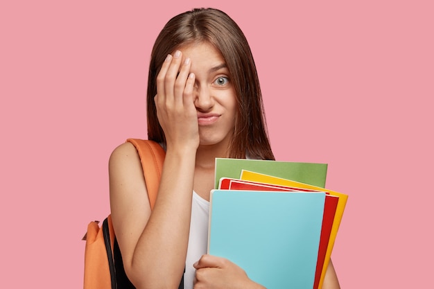 Free photo displeased european teenager covers face with frustrated expression, feels tired