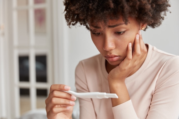 Free photo displeased frustrated african american woman looks stressfully at pregnancy test