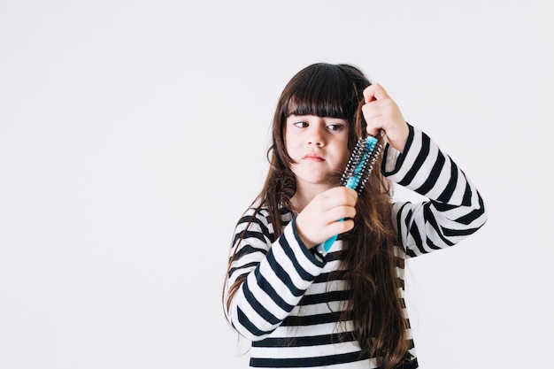 Displeased girl combing hair