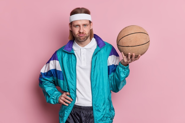 Free photo displeased man basketball player holds ball looks unhappily at camera