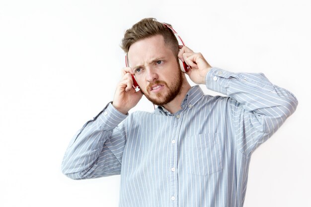 Displeased man listening to music in headphones