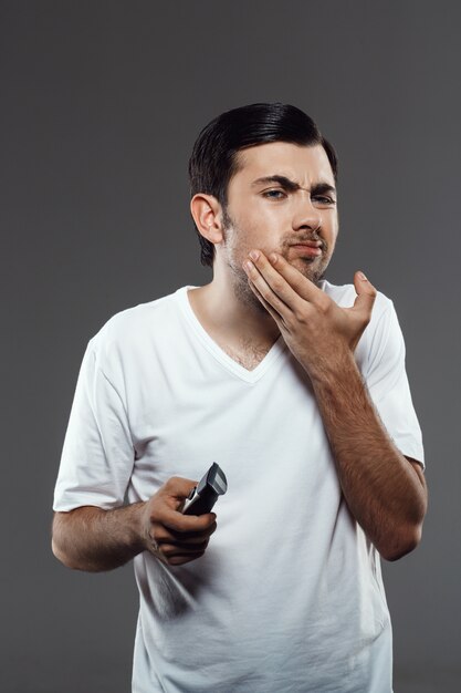 Недоволен человек бритья с электрической бритвой