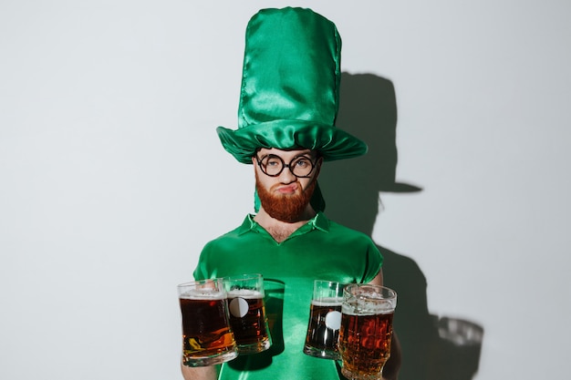 Free photo displeased man in st.patriks costume holding many cups