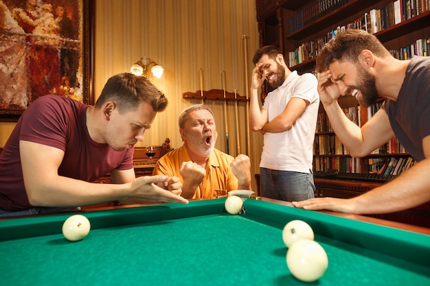 The displeased men playing billiards at office or home after work.