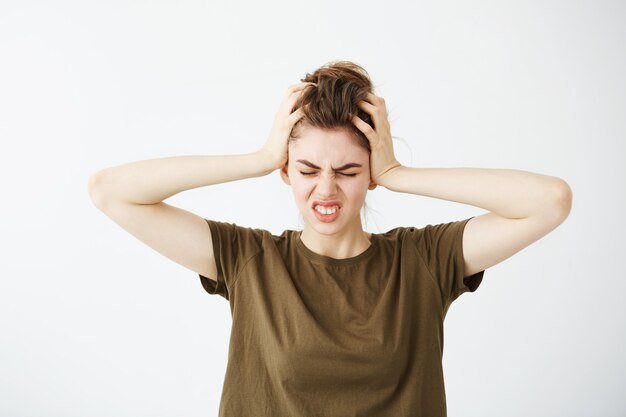 Displeased nervous young woman holding head. Headache.