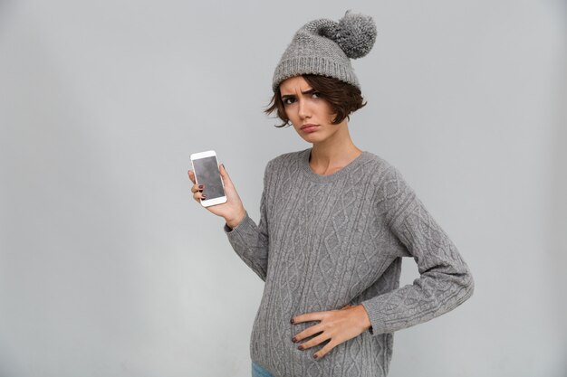 Displeased sad young woman showing display of mobile phone.