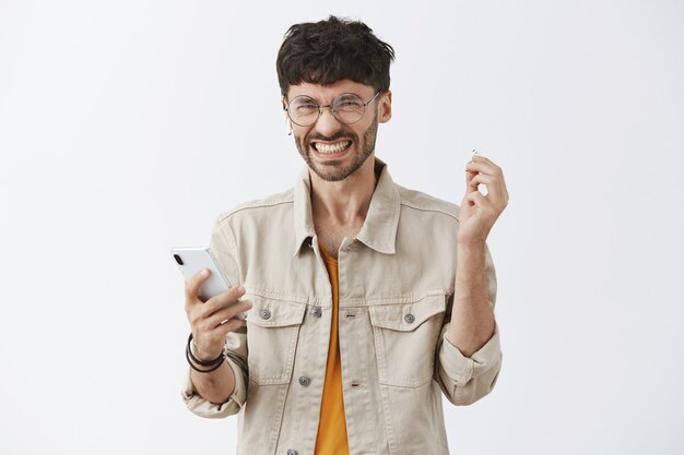 Displeased stylish bearded guy posing against the white wall