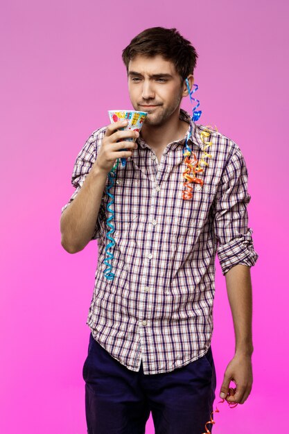 Displeased tired man at birthday party over purple wall.