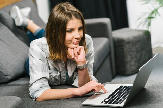 Displeased woman browsing laptop on sofa