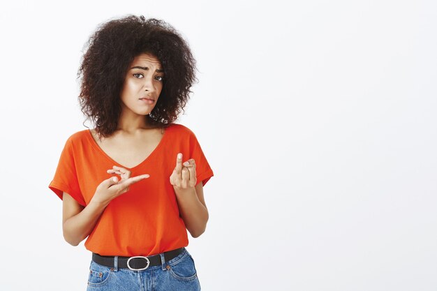 Displeased woman with afro hairstyle posing in the studio