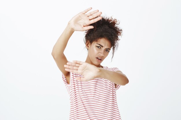 displeased woman with afro hairstyle posing in the studio