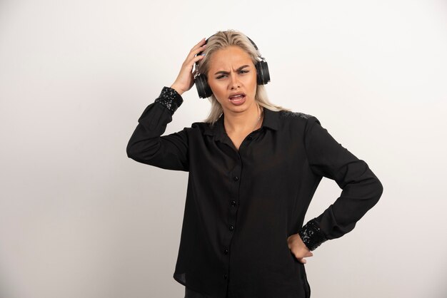 Displeased woman with headphones standing on white background. High quality photo