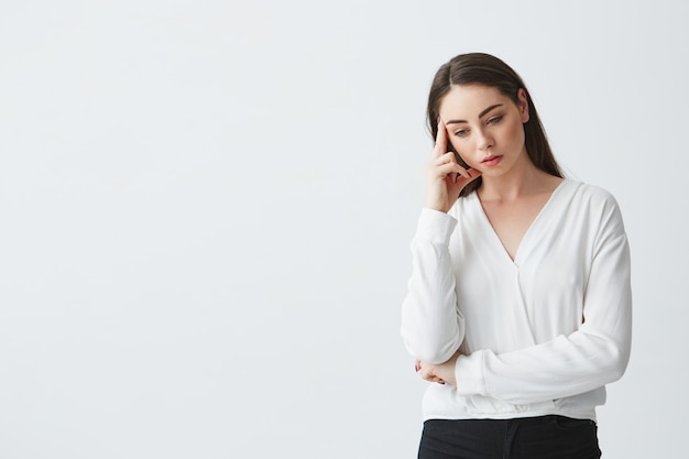 Free photo displeased young beautiful businesswoman thinking looking down with finger near temple .