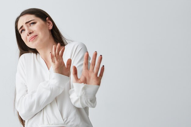 Displeased young beautiful woman showing stop stretching from camera .