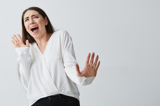 Displeased young beautiful woman showing stop stretching from camera .