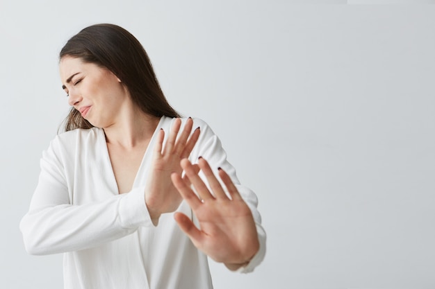 Displeased young beautiful woman showing stop stretching from camera .