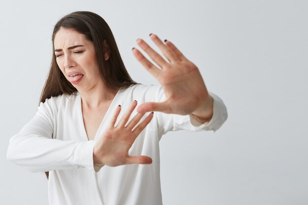 Displeased young beautiful woman showing stop stretching from camera .