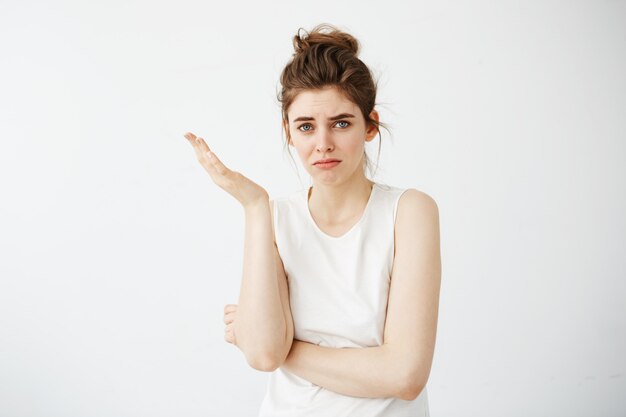 Displeased young beautiful woman with bun gesturing.