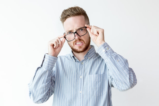 Displeased young businessman adjusting eyeglasses