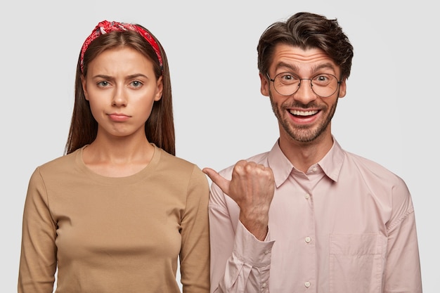 Displeased young couple posing against the white wall