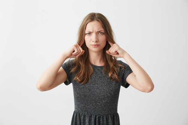 Free photo displeased young girl closing ears frowning .