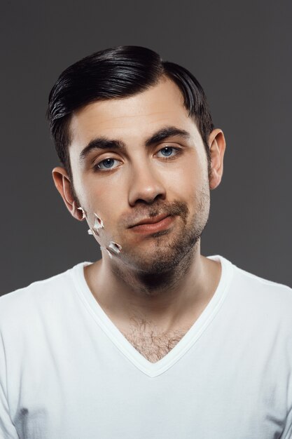 Displeased young man after shaving on grey