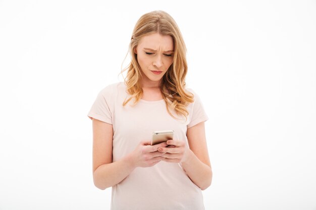 Displeased young woman using mobile phone.