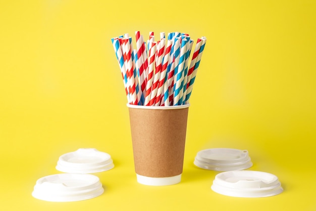 Free photo disposable paper cup with striped paper straws on a yellow background