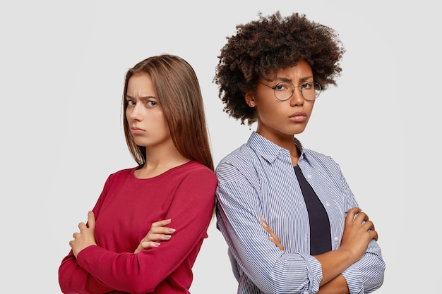 Free photo dissatisfied girlfriends posing against the white wall