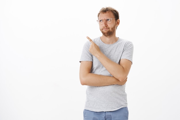 Free photo dissatisfied man pointing at copyspace