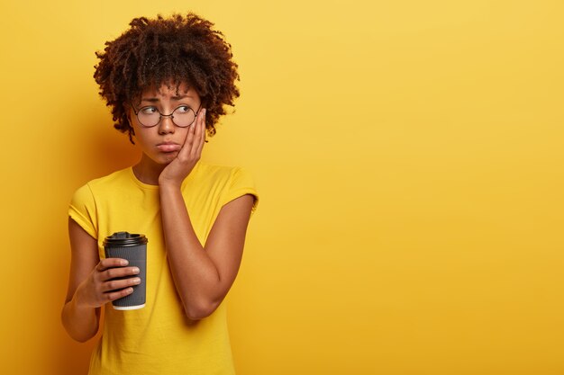 Dissatisfied offended dark skinned woman with Afro haircut looks aside in displeasure, feels lonely