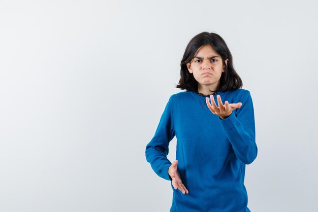 The dissatisfied teenage girl is pointing to camera with hand on white background