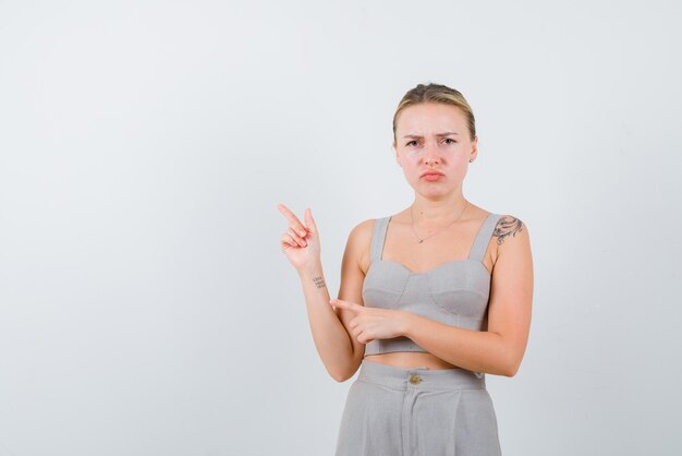 The dissatisfied woman is poinitng to left with forefinger  with hand on white background