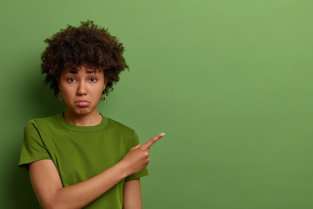 Free photo disstressed unhappy young african american woman sad to miss good opportunity, cant afford to buy expensive thing, looks upset and dissatisfied, frowns and sulks, wears casual green t shirt.