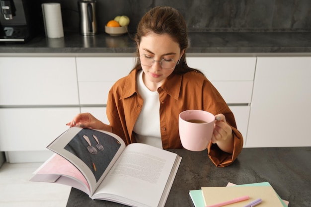 Бесплатное фото Молодая женщина, обучающаяся на расстоянии, учится дома, пьет чай и читает свою работу.