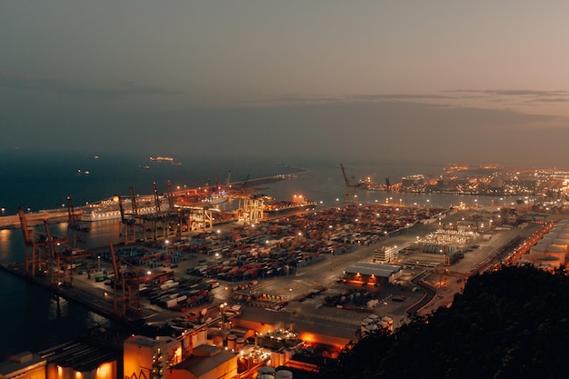 Distant shot of a port with boats loaded with cargo and shipment during nighttime