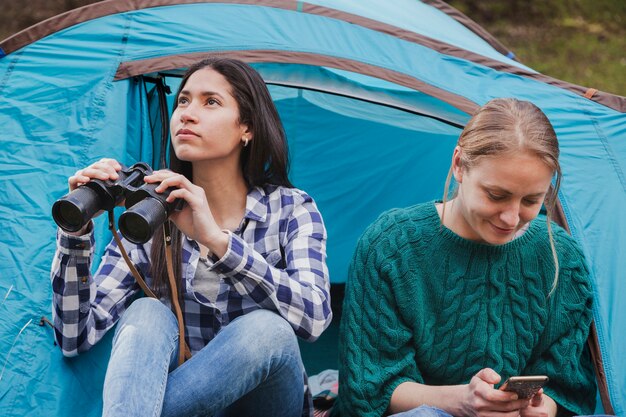 Distracted girls with binoculars and mobile phone