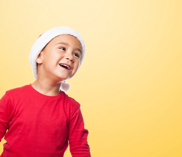 Free photo distracted kid wearing santa claus hat