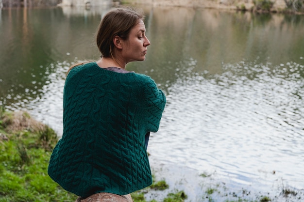 Free photo distracted young woman sitting by the river