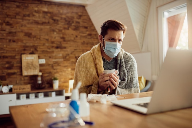 Distraught man with face having cup of tea during video call with a doctor from home