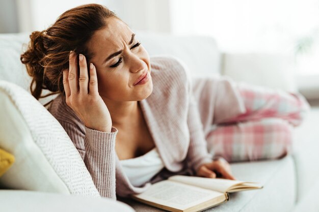 У обезумевшей женщины сильная головная боль, когда она лежит дома на диване