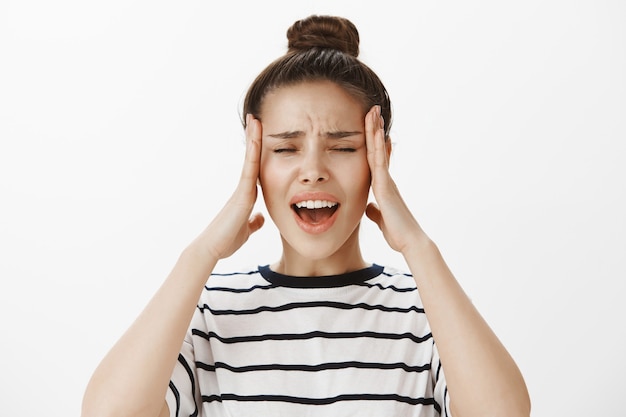 Distressed and bothered girl complaining on headache, rubbing tempels and grimacing frustrated