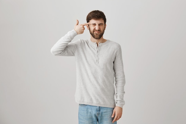 Distressed bothered guy making gun gesture near head