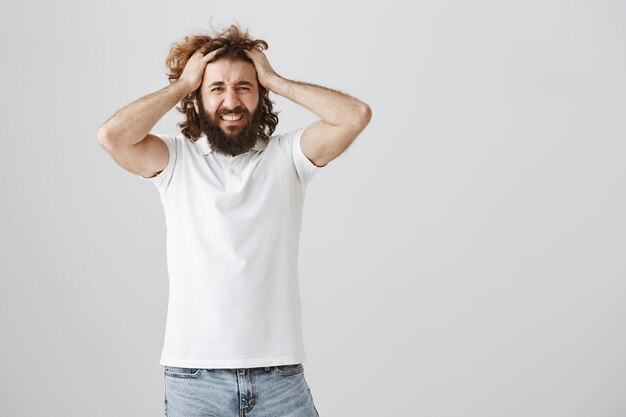 Distressed frustrated middle-eastern man panicking, grab head and grimacing troubled