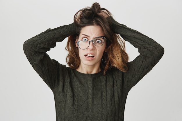 Distressed woman in panic, wearing crooked glasses and tousle hair alarmed