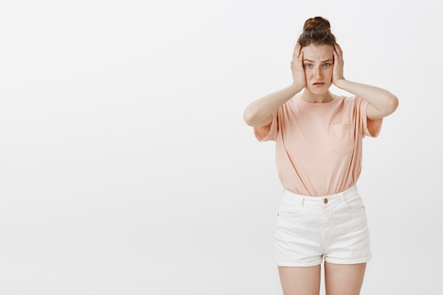 Обеспокоенная и обеспокоенная девочка-подросток позирует у белой стены