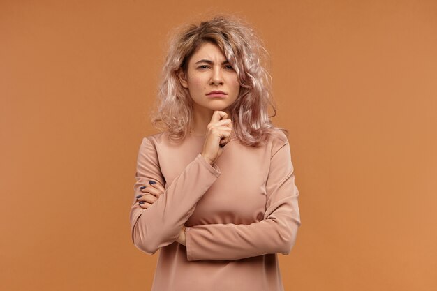 distrust and suspicion concept. isolated shot of stylish hipster girl touching chin