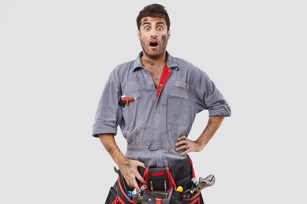 Disturbed surprised craftsman posing against the white wall