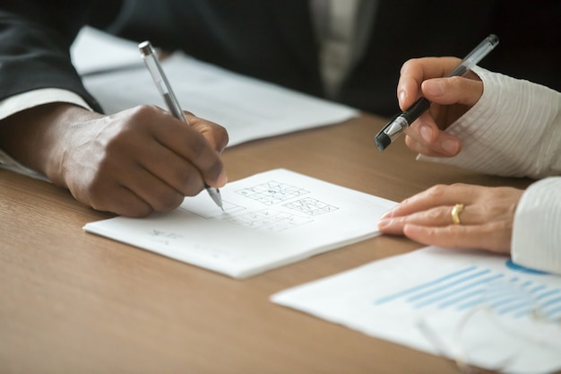 Free photo diverse business partners playing tic-tac-toe game at office desk, closeup