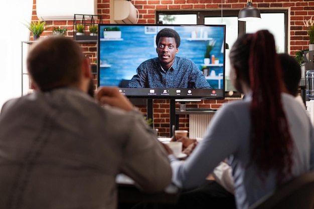 Foto gratuita diversi team di lavoro che discutono idee di partnership con il gestore remoto durante la riunione di videochiamata online che lavora alla presentazione dell'azienda nell'ufficio di avvio. conferenza di chiamata di lavoro sul monitor